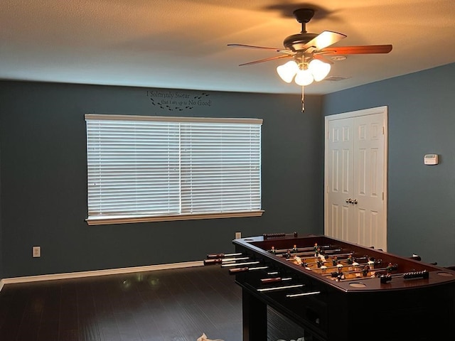 recreation room featuring ceiling fan, dark wood finished floors, and baseboards