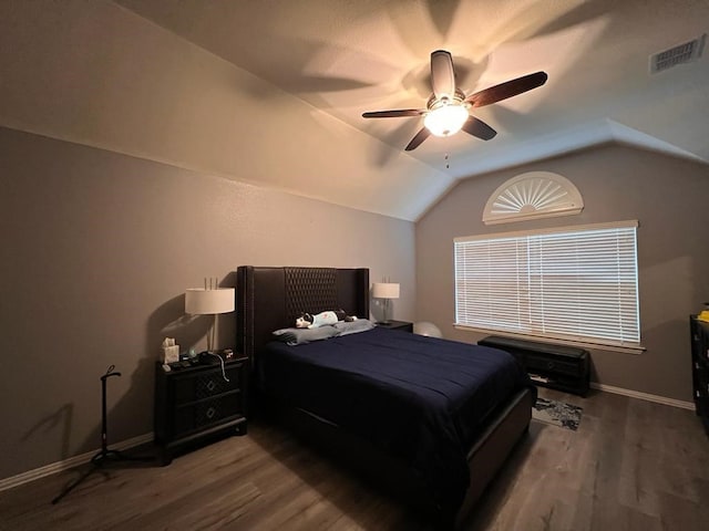 bedroom with vaulted ceiling, wood finished floors, visible vents, and baseboards