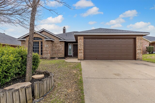 view of front of home with a garage, driveway, roof with shingles, fence, and brick siding