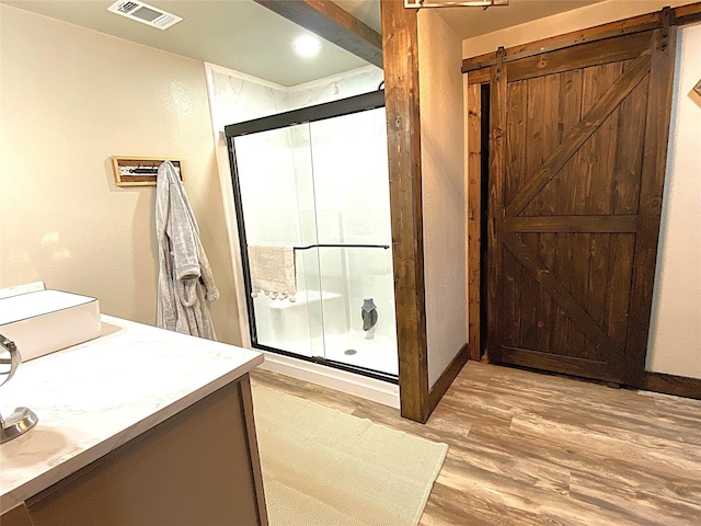 full bath featuring visible vents, a shower stall, vanity, wood finished floors, and baseboards