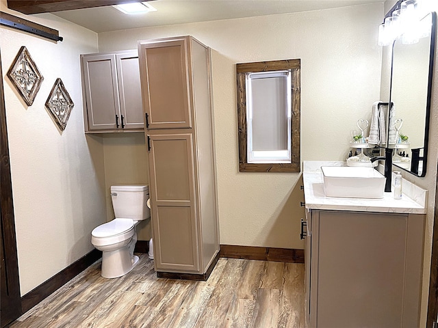 bathroom with vanity, wood finished floors, toilet, and baseboards