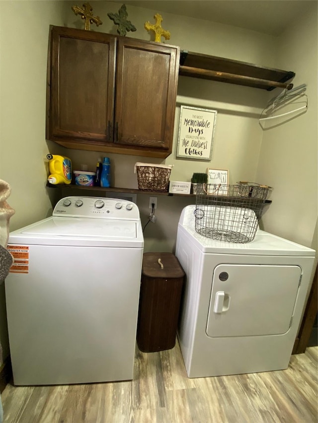 washroom featuring cabinet space, light wood finished floors, and washing machine and clothes dryer