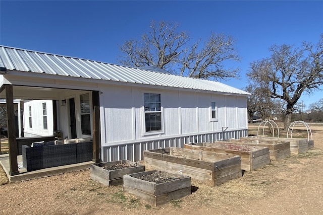 rear view of property with metal roof, outdoor lounge area, and a vegetable garden