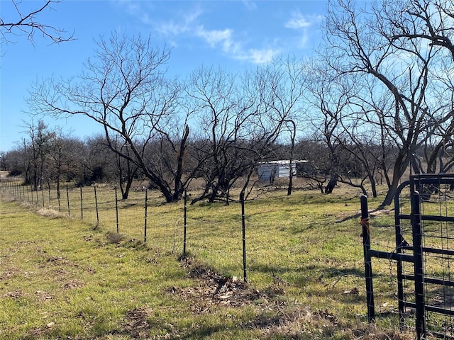 view of yard with fence and a rural view