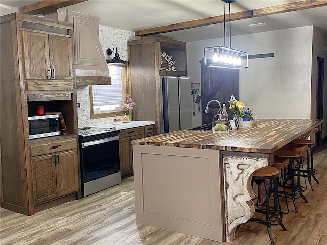 kitchen with wooden counters, appliances with stainless steel finishes, beam ceiling, and light wood-style floors