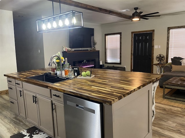 kitchen with open floor plan, wooden counters, stainless steel dishwasher, and a sink