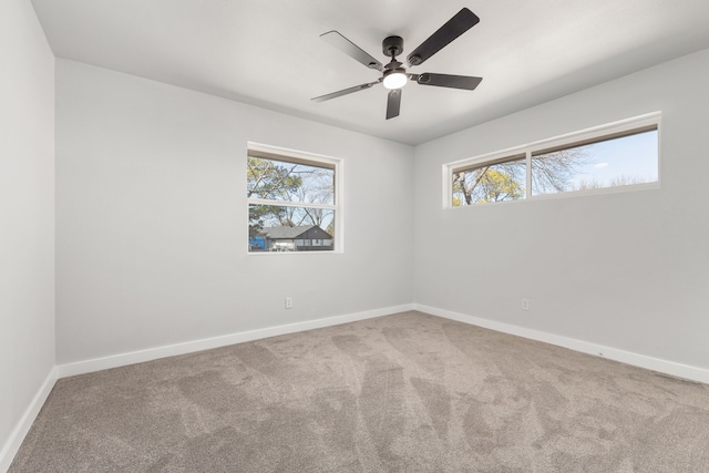 spare room featuring ceiling fan, carpet, a wealth of natural light, and baseboards