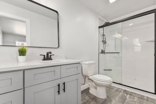 bathroom featuring vanity, a shower stall, toilet, and wood finished floors