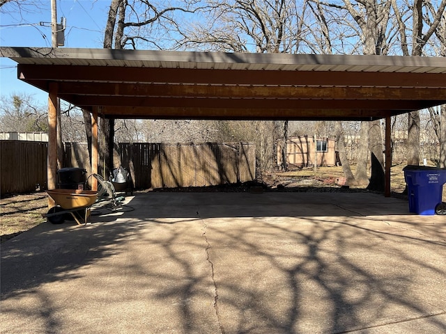 view of parking / parking lot with a carport, driveway, and fence