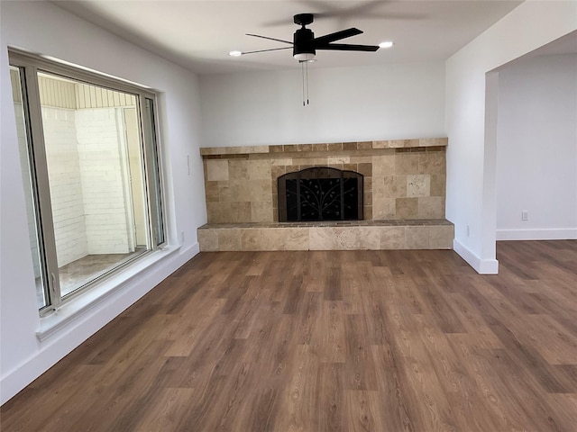 unfurnished living room featuring a fireplace, wood finished floors, a ceiling fan, and baseboards