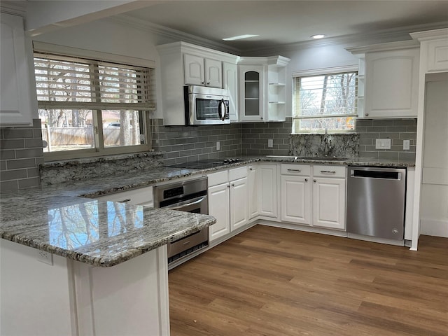 kitchen featuring stainless steel appliances, a peninsula, white cabinets, and crown molding