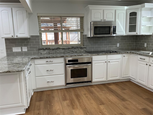 kitchen with light wood-style floors, white cabinetry, stainless steel appliances, and decorative backsplash