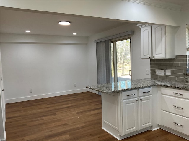 kitchen featuring a peninsula, white cabinetry, baseboards, tasteful backsplash, and dark wood finished floors