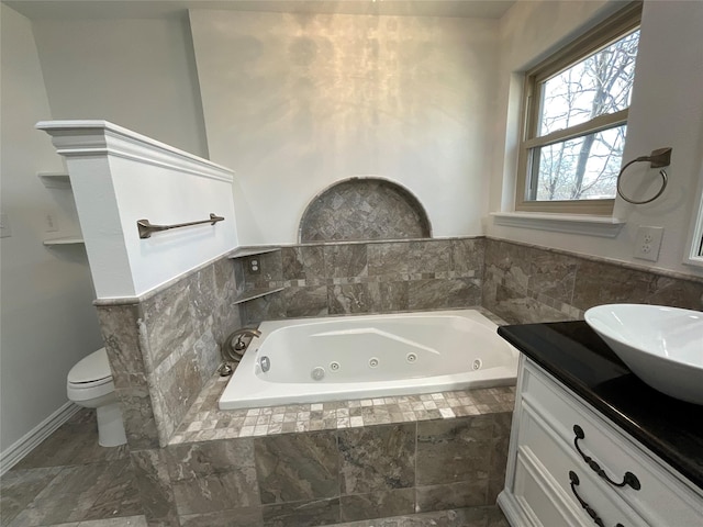 full bathroom featuring a whirlpool tub, toilet, and vanity