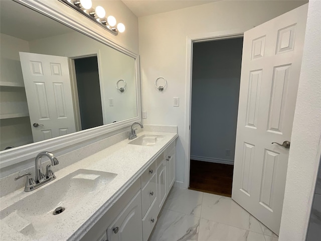 bathroom with marble finish floor, a sink, baseboards, and double vanity