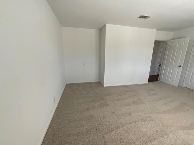 empty room featuring light carpet, baseboards, and visible vents