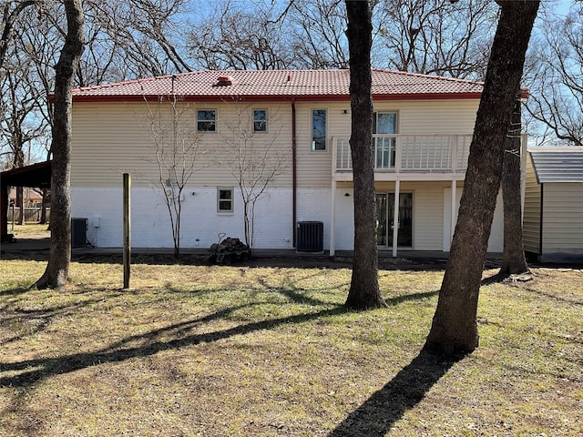 rear view of house with a balcony, a yard, cooling unit, and brick siding