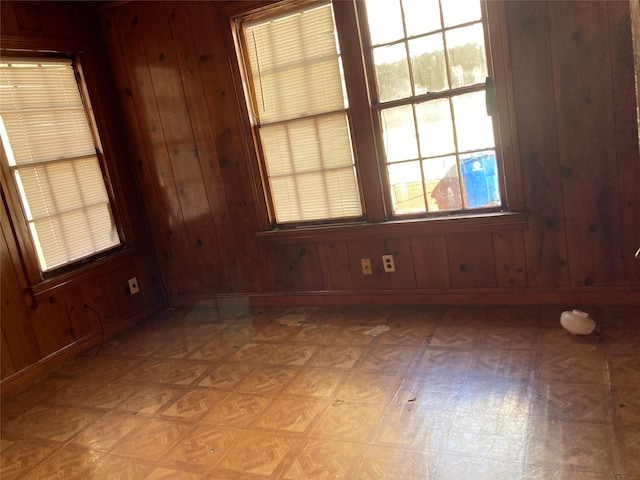 unfurnished room with wood walls, baseboards, and light floors