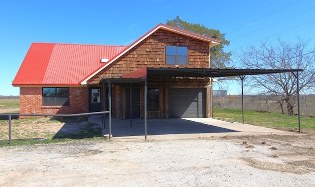 view of front facade featuring metal roof, an attached carport, a garage, brick siding, and driveway