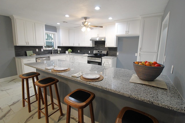 kitchen featuring recessed lighting, stainless steel appliances, white cabinets, marble finish floor, and tasteful backsplash