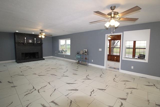 unfurnished living room with a textured ceiling, marble finish floor, a fireplace, and baseboards