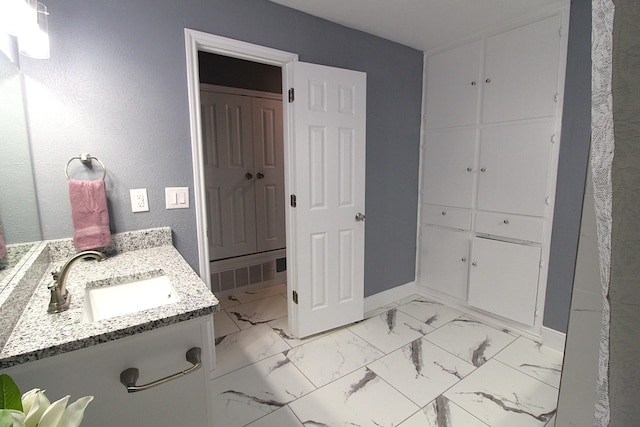 bathroom with marble finish floor, baseboards, and vanity