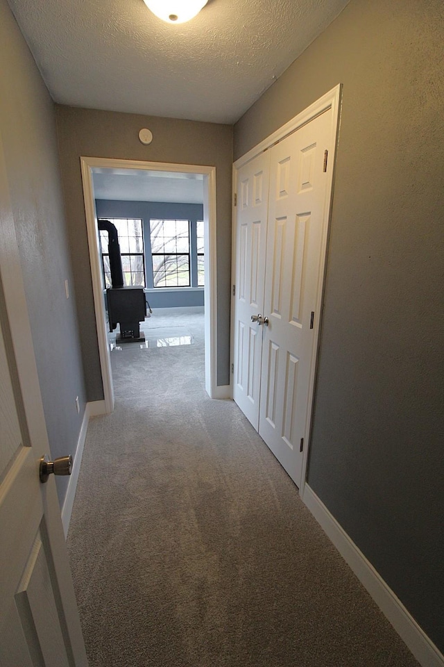 corridor with carpet floors, a textured ceiling, and baseboards