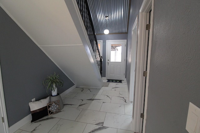 entryway featuring marble finish floor, stairway, and baseboards