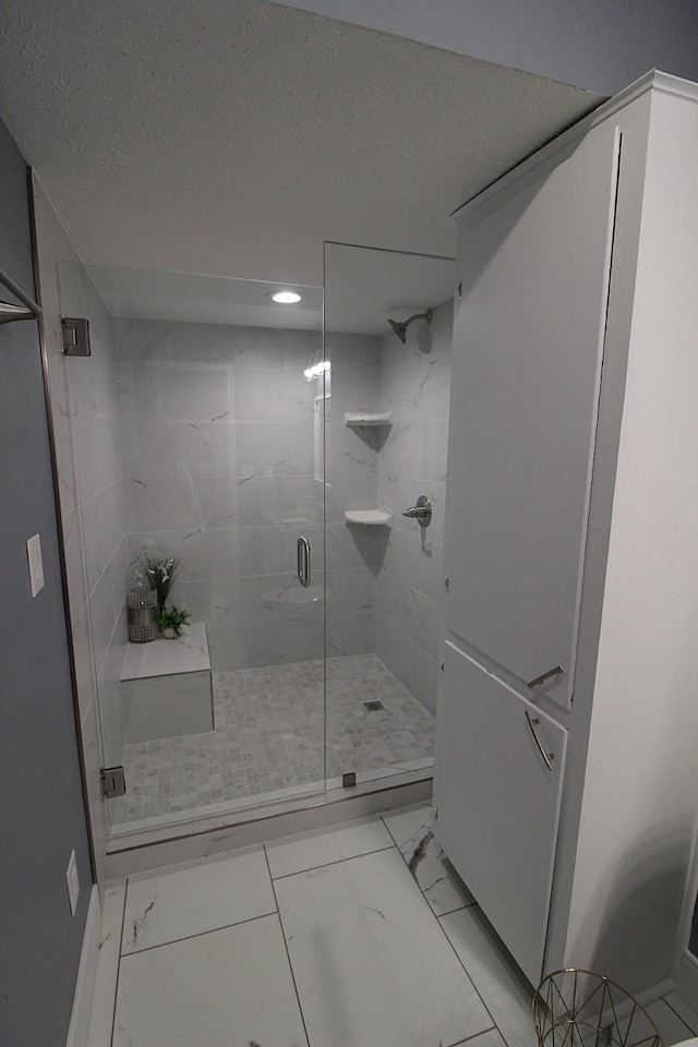 full bath featuring a stall shower, marble finish floor, and a textured ceiling