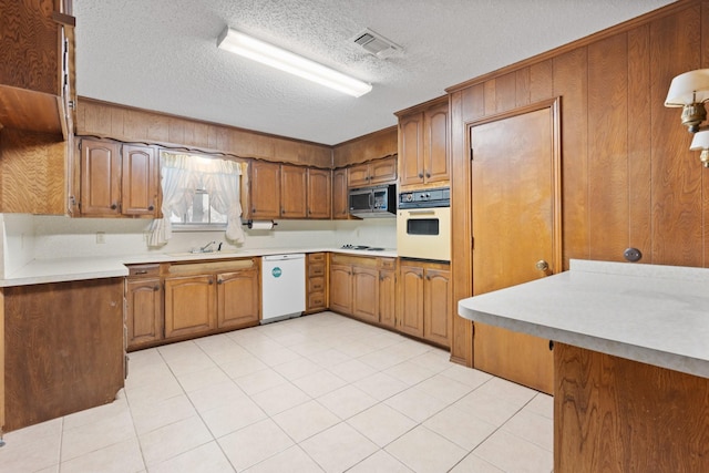 kitchen featuring white appliances, visible vents, brown cabinets, light countertops, and a textured ceiling