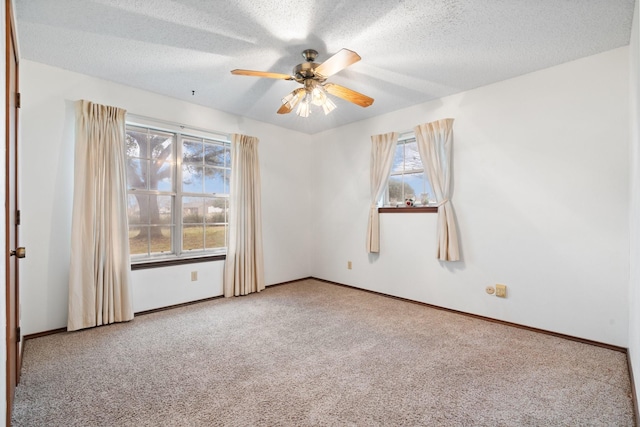 carpeted empty room with a ceiling fan, baseboards, and a textured ceiling