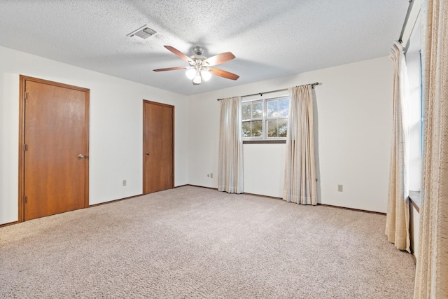 unfurnished bedroom with light carpet, a textured ceiling, visible vents, and a ceiling fan