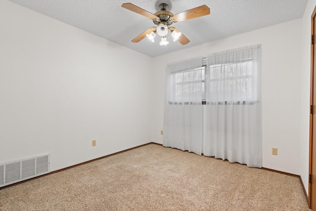 carpeted spare room with baseboards, visible vents, ceiling fan, and a textured ceiling