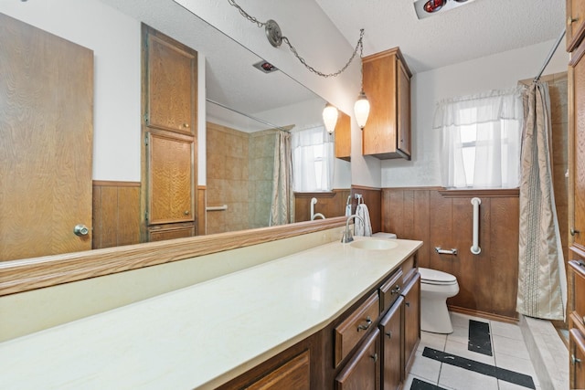 full bathroom featuring a wainscoted wall, toilet, wooden walls, a textured ceiling, and tile patterned floors