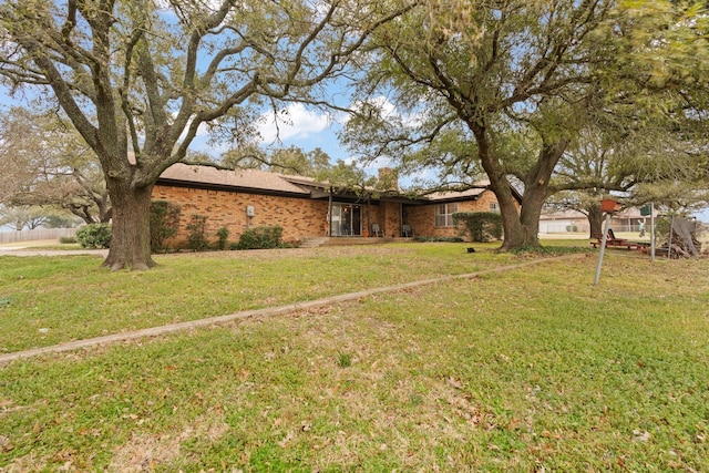 exterior space featuring brick siding, a front lawn, and a chimney