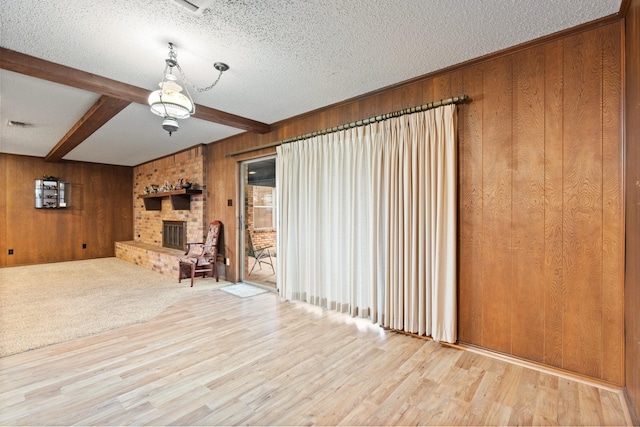 unfurnished living room with a fireplace, beam ceiling, and wooden walls