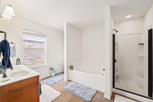 bathroom with double vanity, a sink, a shower stall, baseboards, and a bath