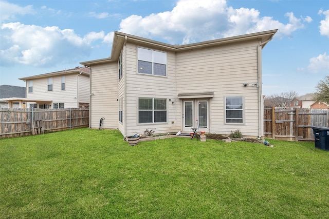 rear view of house with a fenced backyard and a lawn