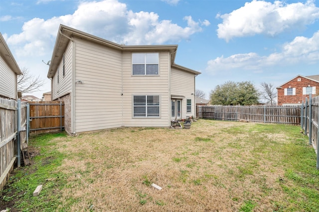 back of property with a fenced backyard and a yard