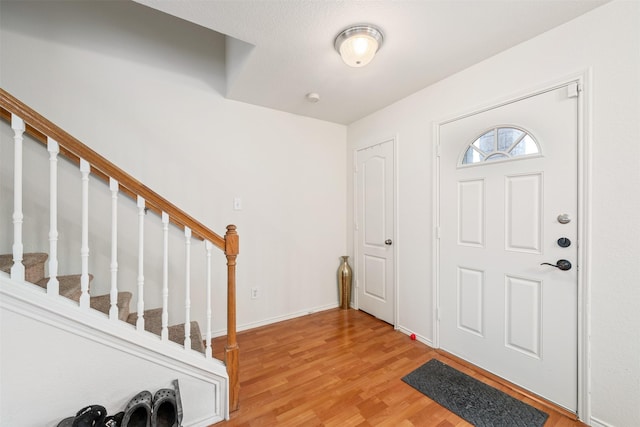 foyer featuring light wood-type flooring, stairway, and baseboards