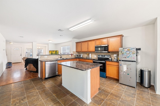 kitchen with stainless steel appliances, a peninsula, a sink, visible vents, and decorative backsplash