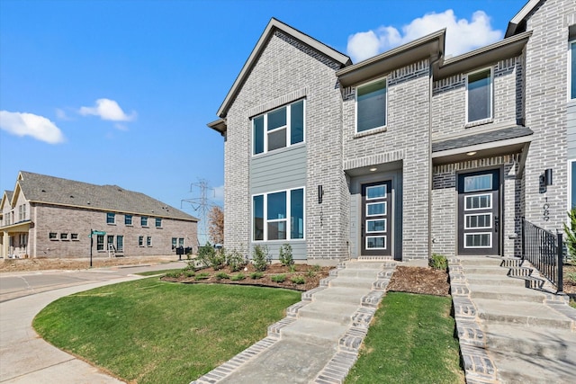 multi unit property featuring brick siding and a front lawn