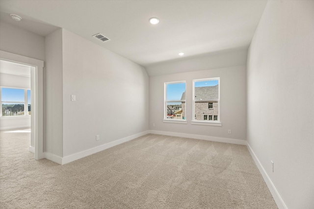 empty room featuring baseboards, visible vents, a wealth of natural light, and light colored carpet