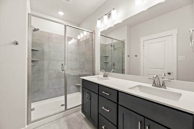 bathroom featuring a sink, a shower stall, and double vanity