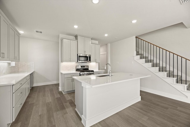 kitchen with dark wood-type flooring, a sink, visible vents, appliances with stainless steel finishes, and decorative backsplash