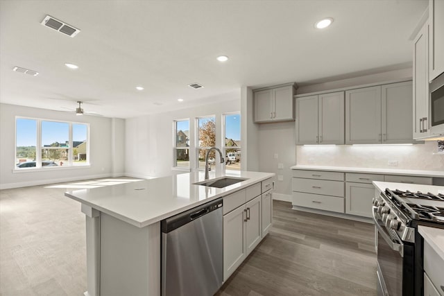 kitchen featuring stainless steel appliances, tasteful backsplash, light countertops, visible vents, and a sink