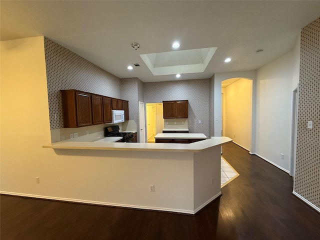 kitchen featuring black range with gas cooktop, white microwave, recessed lighting, light countertops, and dark wood finished floors