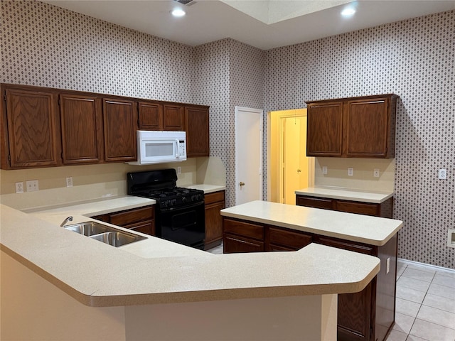 kitchen featuring wallpapered walls, white microwave, black range with gas stovetop, light countertops, and a sink