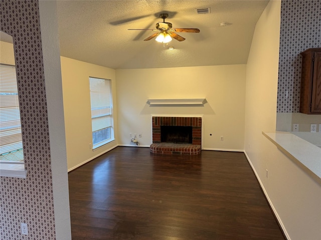 unfurnished living room featuring ceiling fan, wood finished floors, visible vents, baseboards, and a brick fireplace