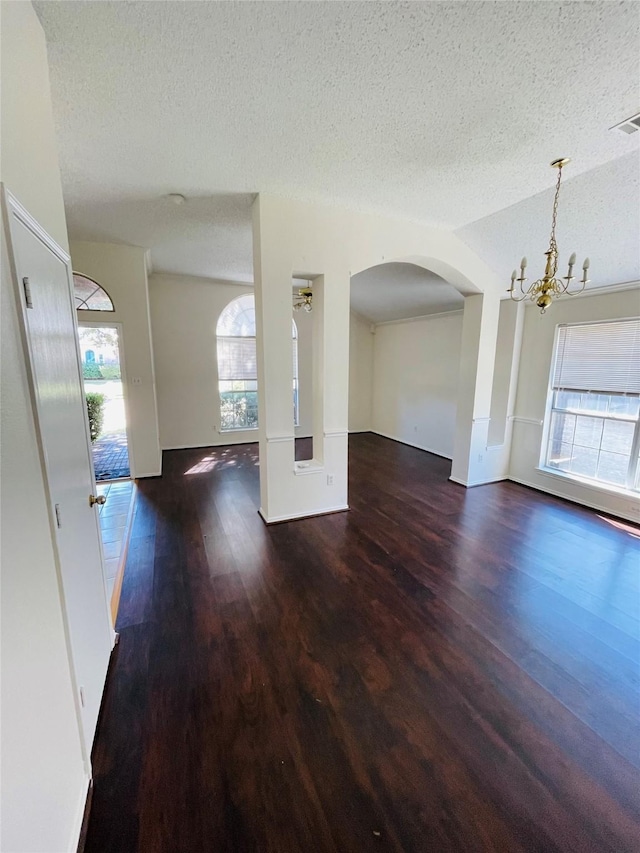 interior space with arched walkways, visible vents, a textured ceiling, and wood finished floors